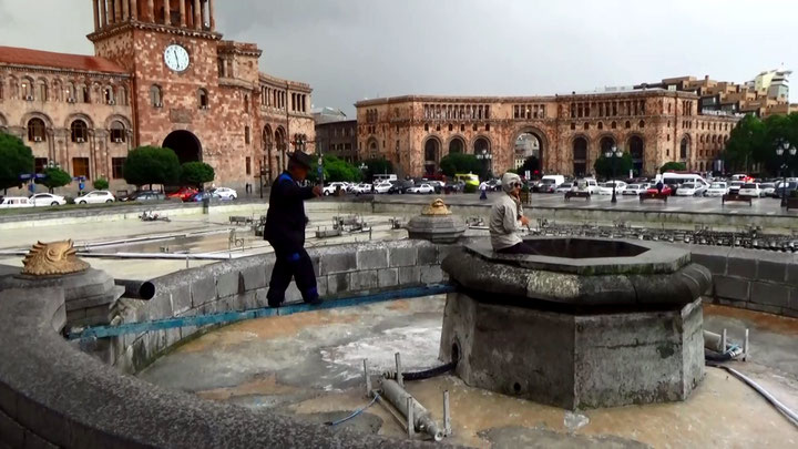 Anna Shahnazaryan et al., <i>Fountain Action. Police threaten Citizen with Psychiatric Ward</i>, 2016, Still; Protagonistin mit Anhänger*innen und Polizisten; eine Wache auf dem Weg zur Protagonistin, um sie aus dem Brunnen zu vertreiben